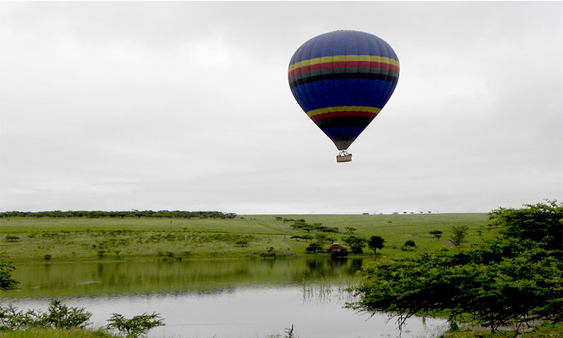 Single balloon drifting above Tala wetlands and green terrain
